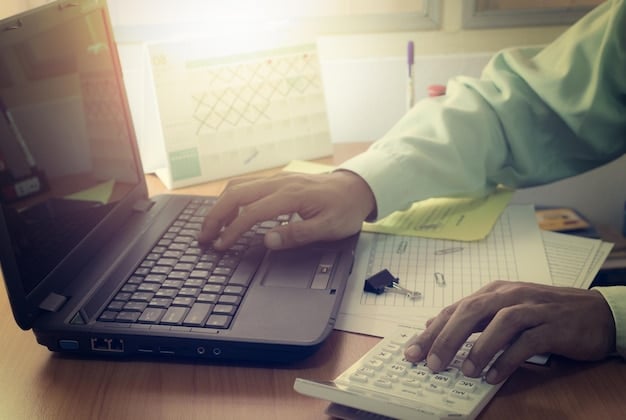 A person reviewing their credit report on a laptop, with financial documents and a calculator in the background, emphasizing the importance of regular monitoring to detect identity theft.