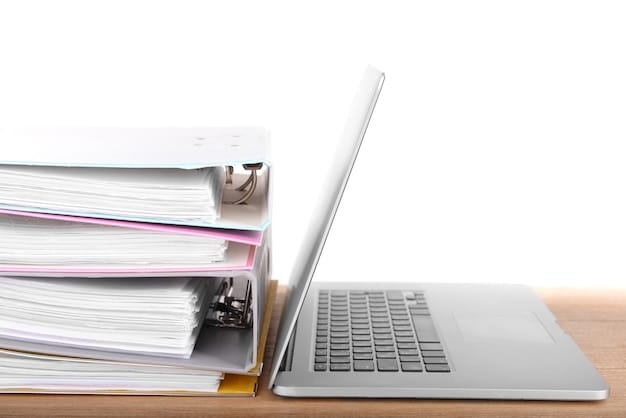 A stack of legal documents representing FCC regulations, sitting on a desk beside a laptop displaying a cybersecurity dashboard with various data breach alerts and security metrics. The scene is lit in a way that emphasizes the contrast between the physical and digital aspects of data privacy compliance.